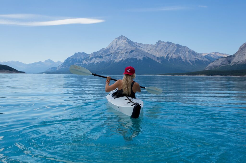 kayaking in crystal-clear water, surrounded by stunning mountains and a peaceful landscape, enjoying a serene outdoor adventure