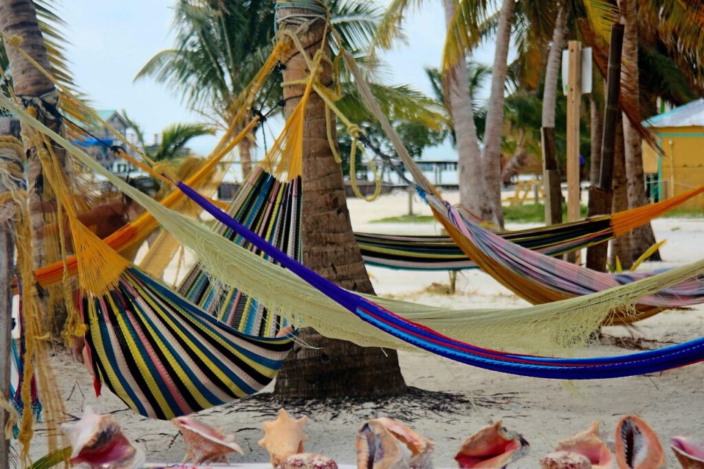 Colorful hammocks tied to palm trees on Ambergris Caye beach, offering a relaxing spot to unwind by the sea
