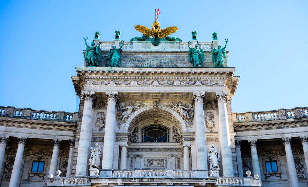 Close-up view of the Hofburg Palace in Vienna, showcasing detailed architecture, statues, and the golden eagle atop the building.