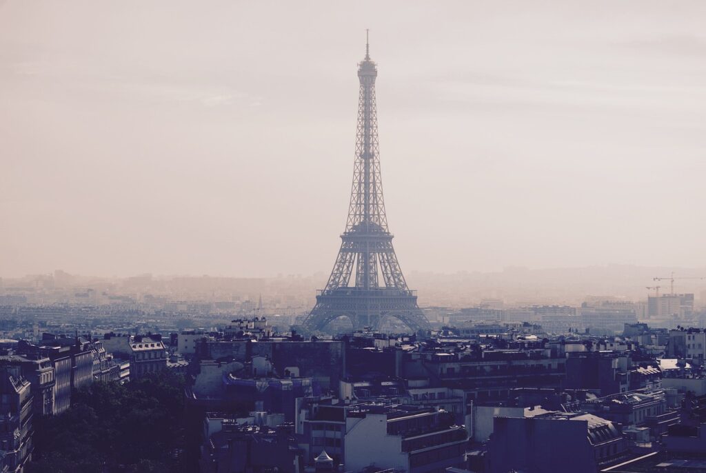 View of the Eiffel Tower in Paris with a hazy skyline, showcasing the iconic landmark and the surrounding cityscape