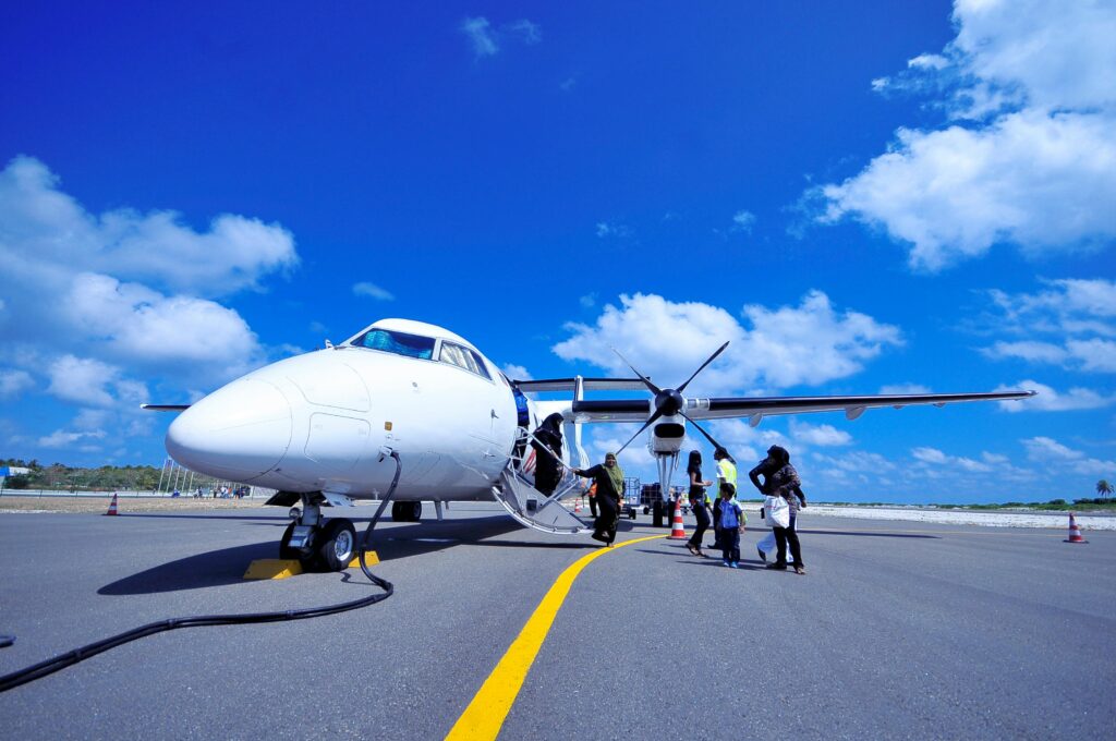 Small airplane at Ambergris Caye airport with passengers disembarking under a clear blue sky, perfect for a scenic island adventure