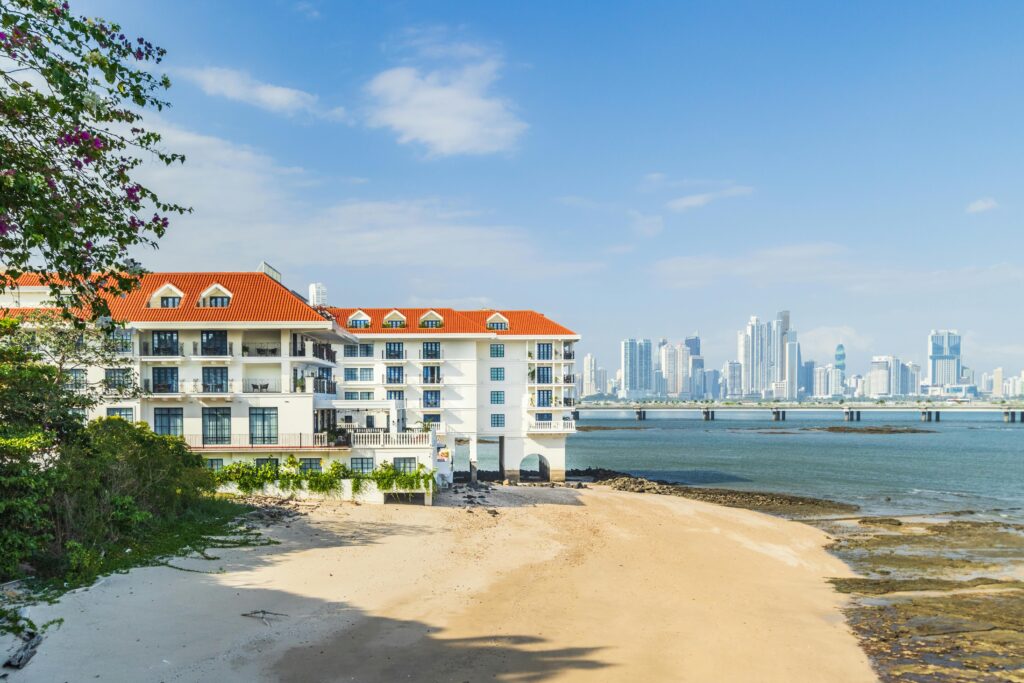 Scenic beach view with a modern beachfront hotel, offering a stunning view of the ocean and city skyline in the background, perfect for a relaxing getaway